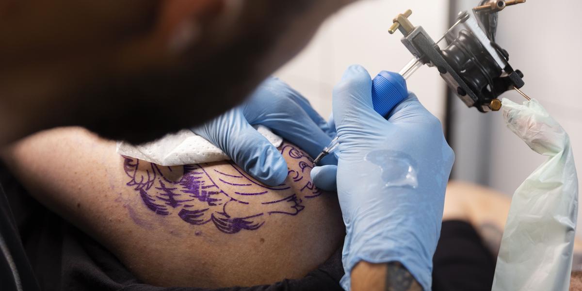 Pablo Santos, tatuador, acha a proibição desnecessária, pois não usa anestesia. Sarah Sanches, empresária com 14 tatuagens, questiona a proibição de anestésicos tópicos. (Freepik)